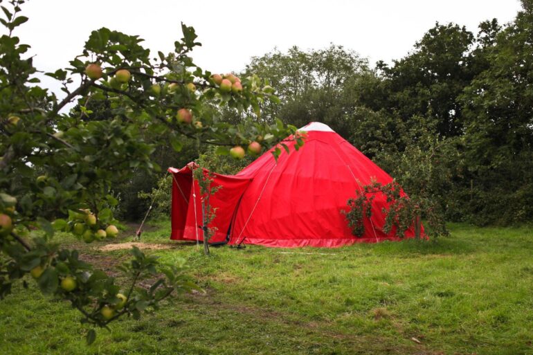 Red tent in a secluded, grassy area