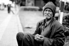 Social programs must fail in a capitalist system: homeless man on the sidewalk